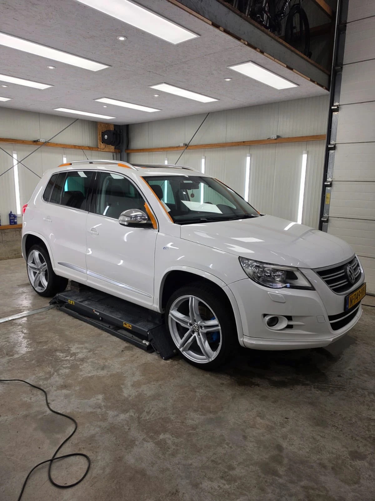 Witte Volkswagen Tiguan R-Line op de brug in de werkplaats tijdens een complete detailbeurt